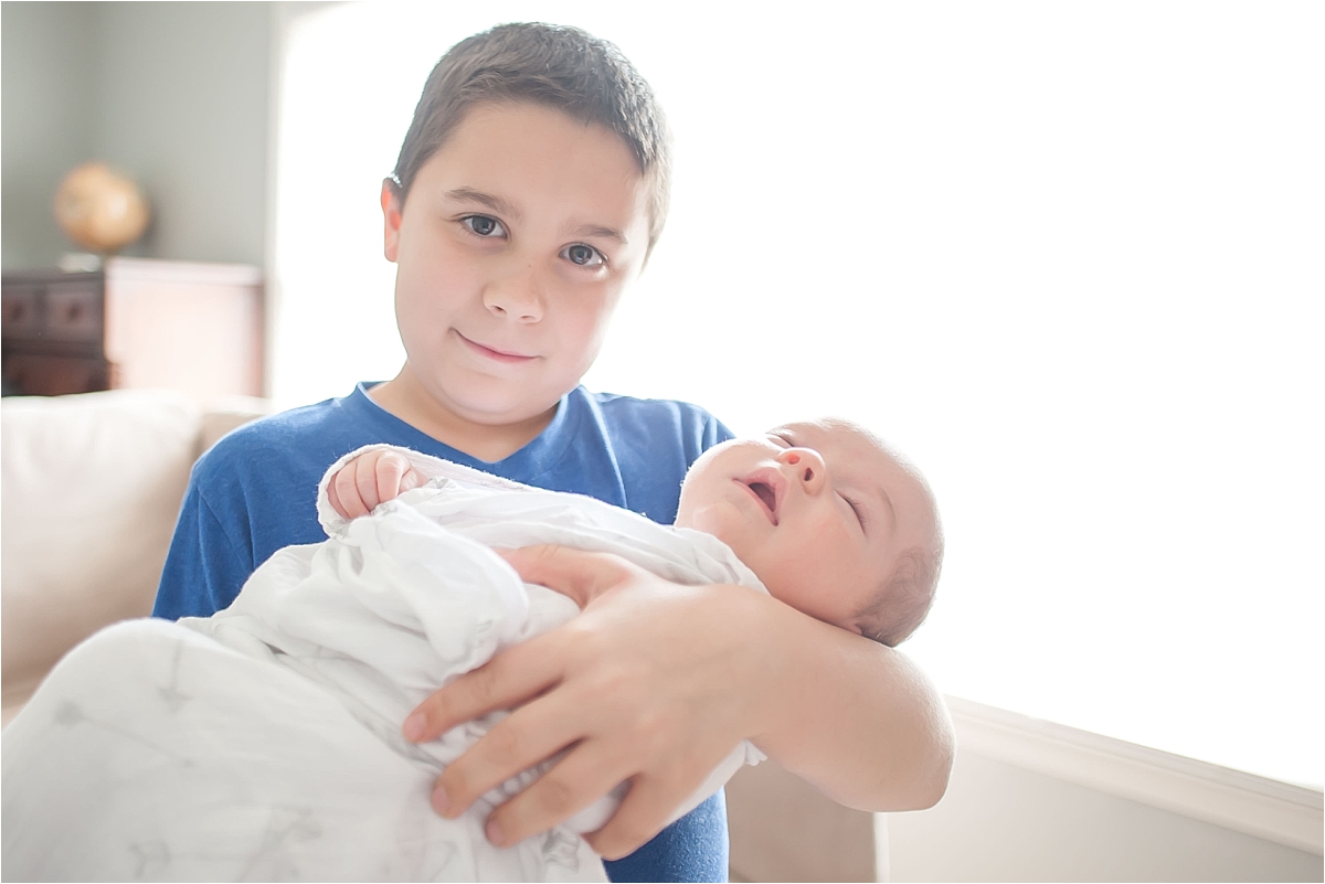 Big brother holding newborn little brother during newborn photography session in Canton GA