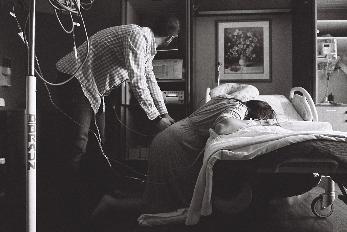 Black and white film photo of birth partner supporting laboring mother during an Atlanta birth photography session at Kennestone Hospital in Metro Atlanta