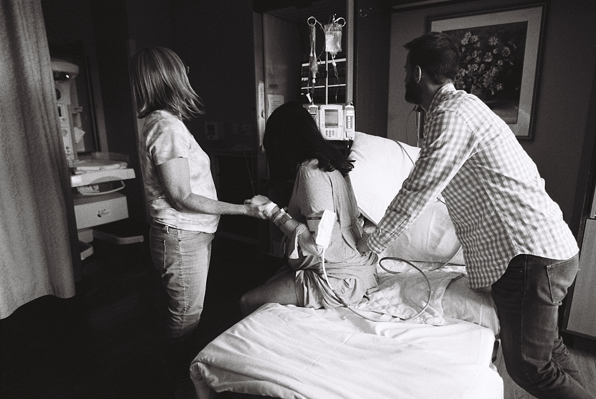Black and white film photo of birth partners supporting laboring mother during an Atlanta birth photography session at Kennestone Hospital in Metro Atlanta
